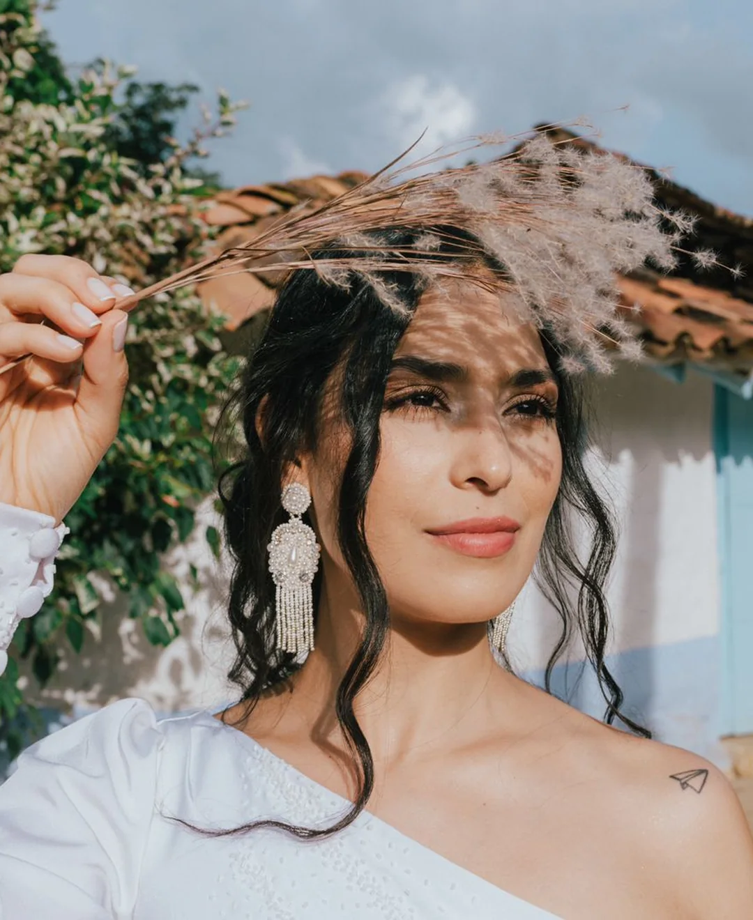 Look bohemio editorial con vestido one-shoulder y plumas en exterior