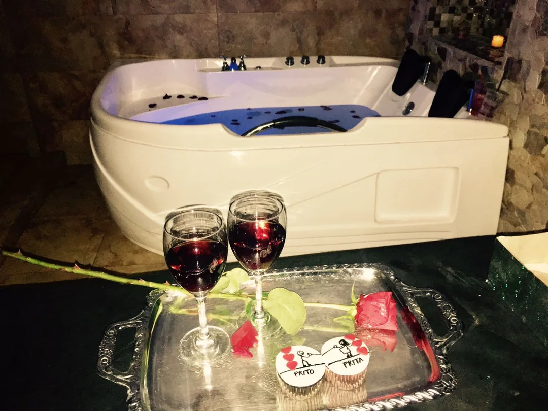 Setup romántico con copas de vino, rosa y cupcakes junto al jacuzzi — paquete pareja